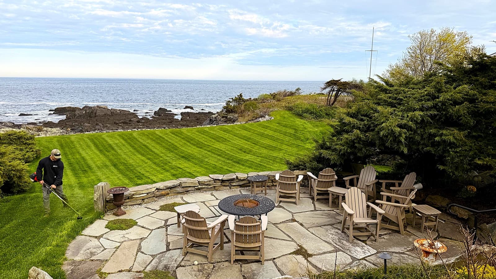 Oceanfront stone patio and fire pit above a striped lawn