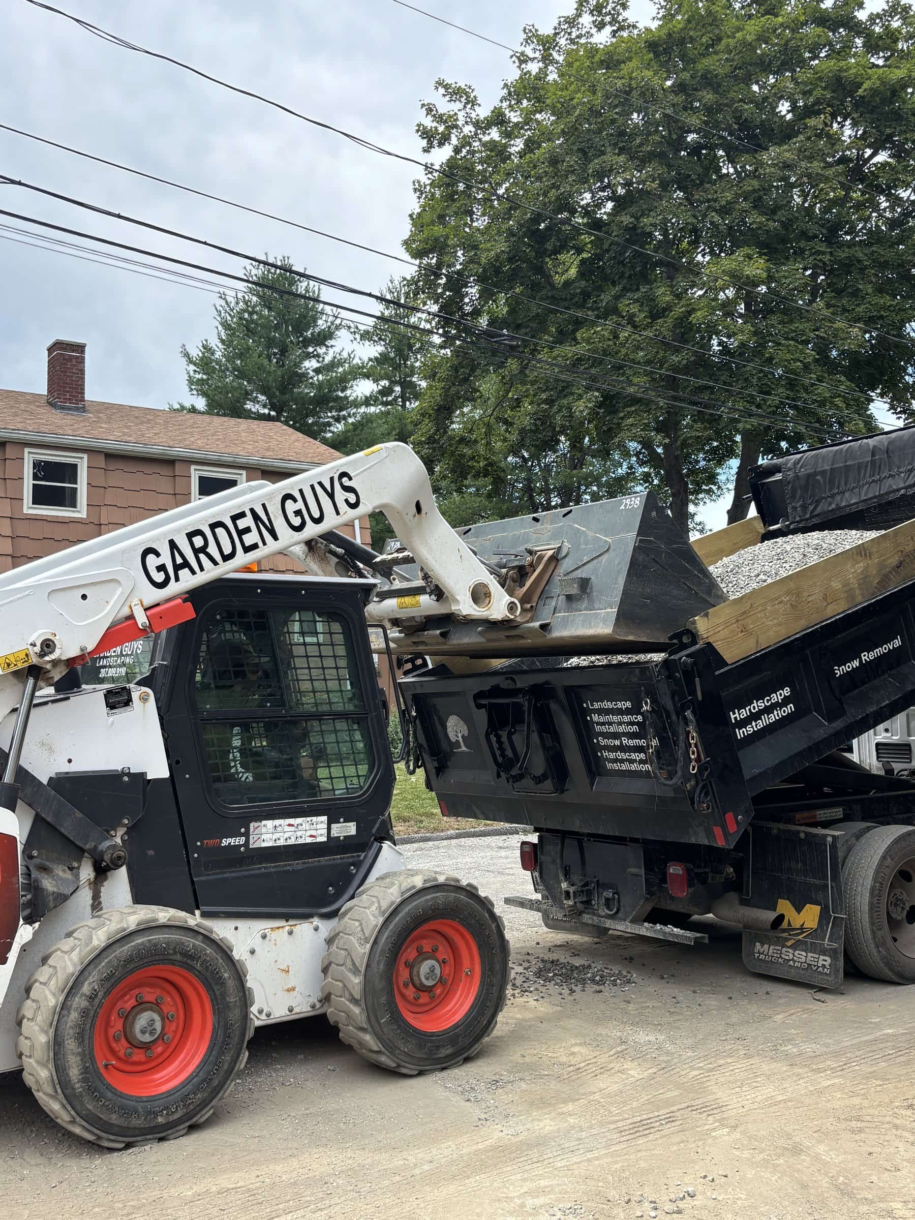 Garden Guys skid steer loading a dump truck